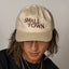 A person wearing a beige baseball cap with 'SMALL TOWN' text embroidered on the front.